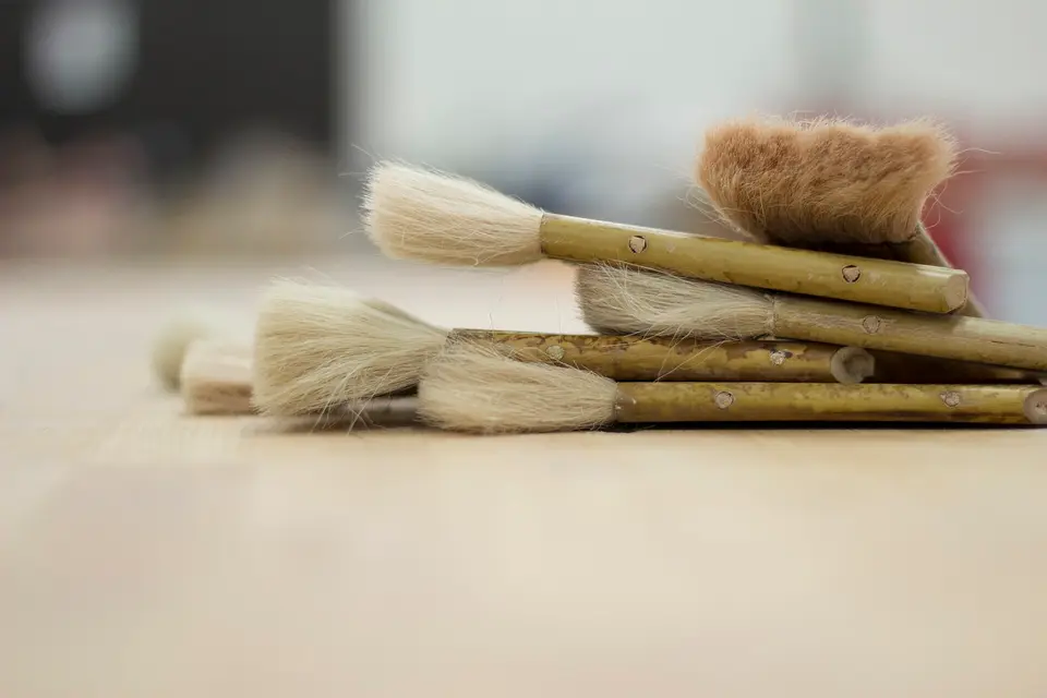 Een paar kwasten met natuurhaar liggen op een licht houten werkblad